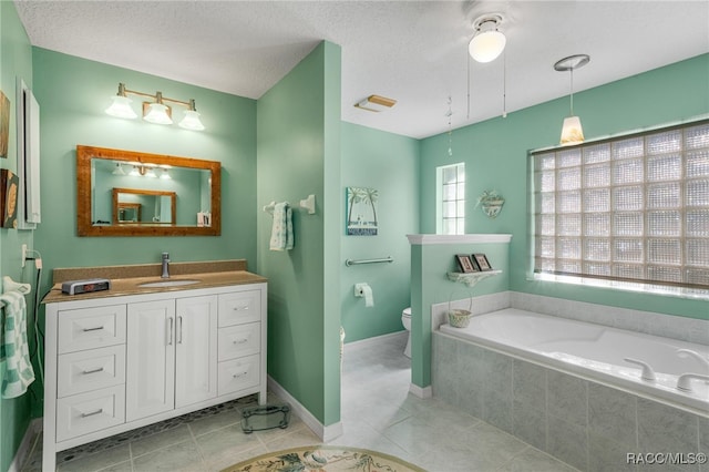 bathroom featuring tile patterned flooring, vanity, tiled tub, and toilet