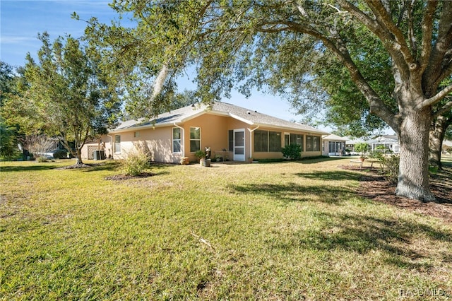 rear view of house with a lawn and a sunroom