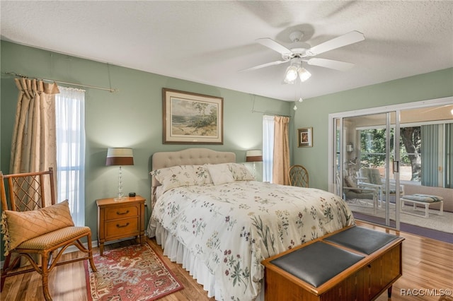 bedroom featuring ceiling fan, wood-type flooring, access to exterior, and a textured ceiling