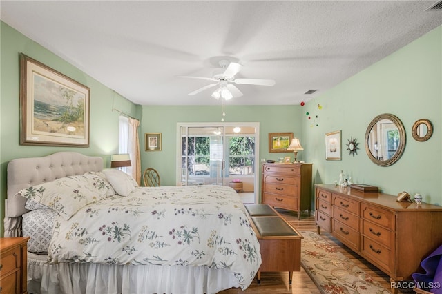 bedroom with ceiling fan, a textured ceiling, and light hardwood / wood-style flooring