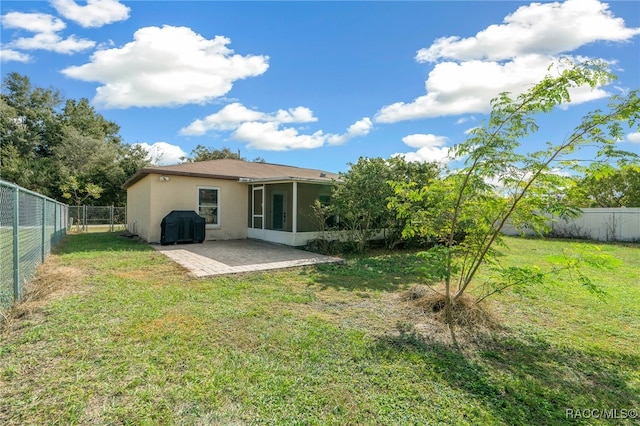 rear view of house featuring a yard, a patio area, and a sunroom