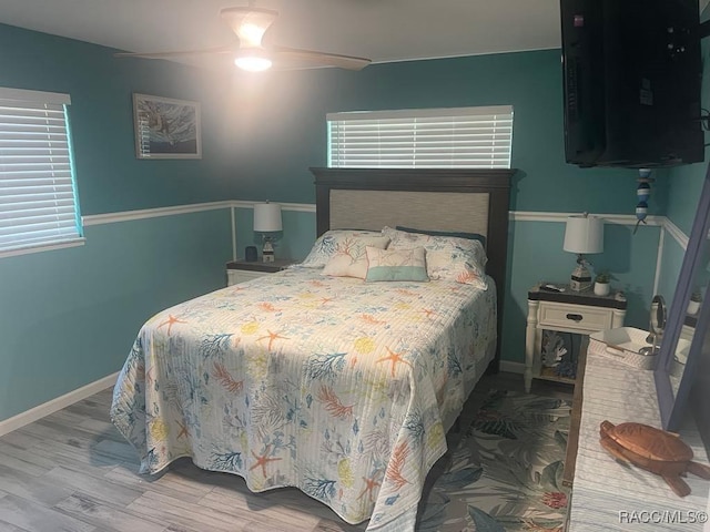 bedroom featuring baseboards, multiple windows, and wood finished floors