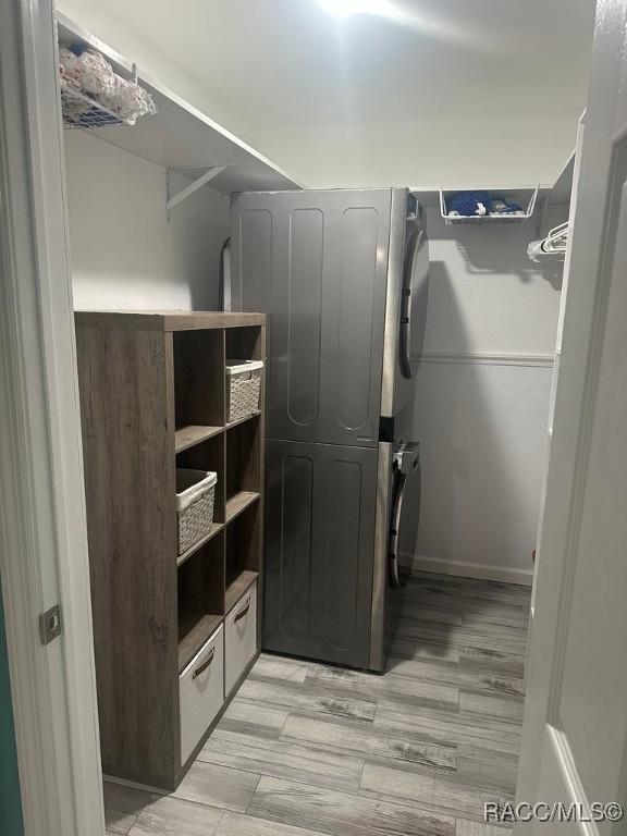 clothes washing area featuring light wood-style floors, stacked washer and dryer, and laundry area