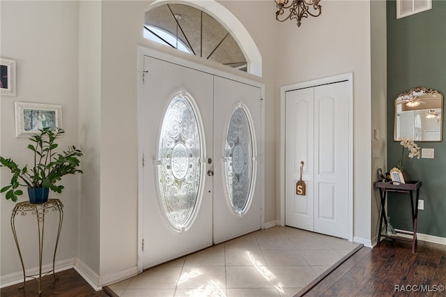 entrance foyer with french doors, hardwood / wood-style floors, and ceiling fan with notable chandelier