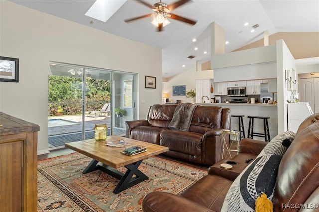 living room featuring a skylight, ceiling fan, hardwood / wood-style floors, and high vaulted ceiling