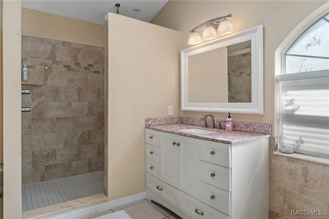 bathroom featuring a tile shower, tile patterned floors, and vanity