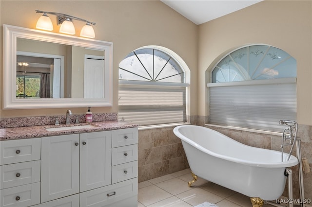 bathroom featuring a tub to relax in, tile patterned flooring, vanity, and tile walls