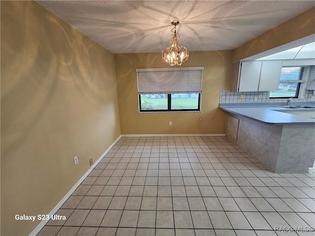 kitchen featuring white cabinets, a textured ceiling, sink, a chandelier, and hanging light fixtures