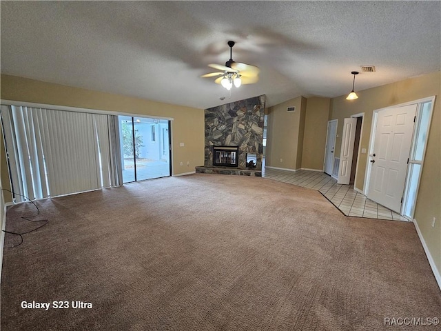 unfurnished living room featuring a stone fireplace, vaulted ceiling, ceiling fan, a textured ceiling, and light colored carpet