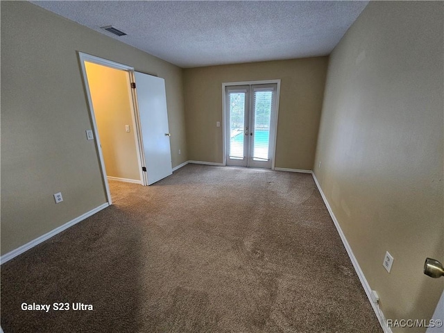 empty room featuring light colored carpet, a textured ceiling, and french doors