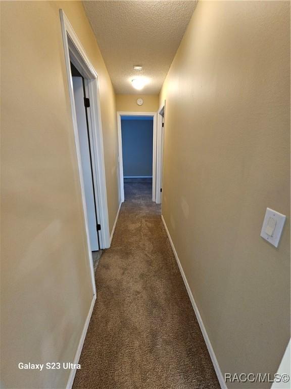 corridor featuring carpet floors and a textured ceiling