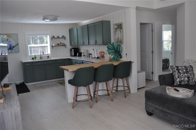 kitchen featuring a breakfast bar area, plenty of natural light, light hardwood / wood-style flooring, and kitchen peninsula