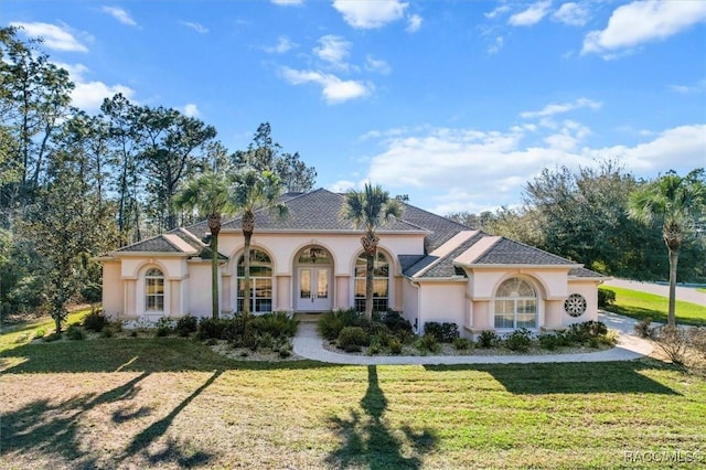 mediterranean / spanish home featuring french doors, a front lawn, and stucco siding