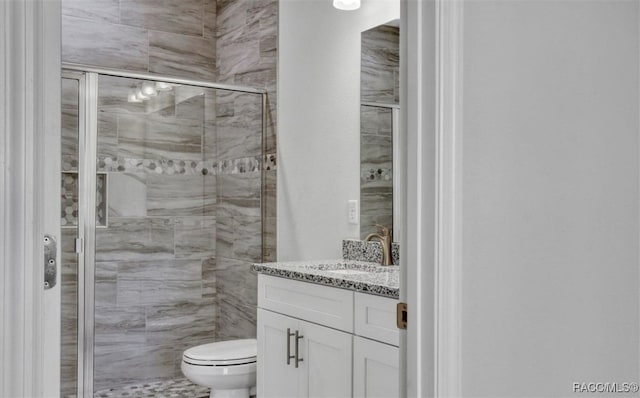 bathroom with vanity, toilet, and a shower with shower door