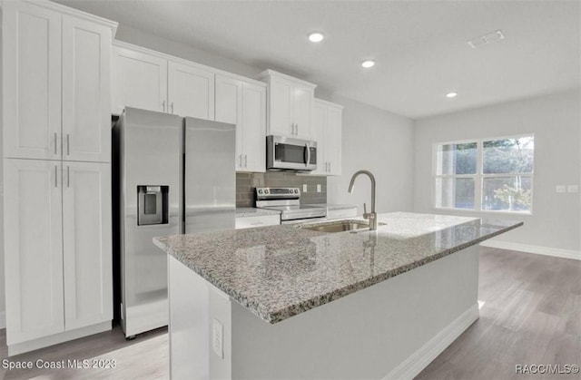 kitchen with appliances with stainless steel finishes, a center island with sink, white cabinetry, and sink