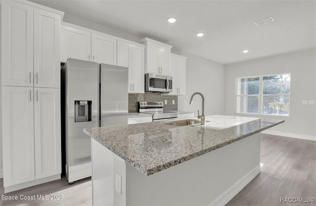 kitchen with white cabinets, an island with sink, stainless steel appliances, and sink