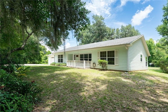 back of property with covered porch and a lawn