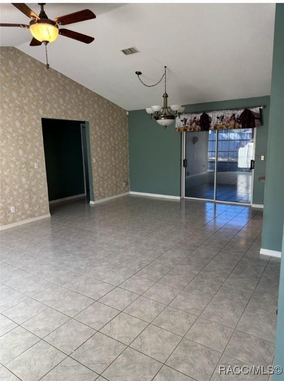 spare room featuring visible vents, wallpapered walls, baseboards, lofted ceiling, and ceiling fan with notable chandelier