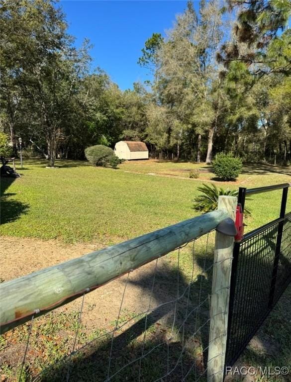 view of yard with an outbuilding, a storage unit, and fence