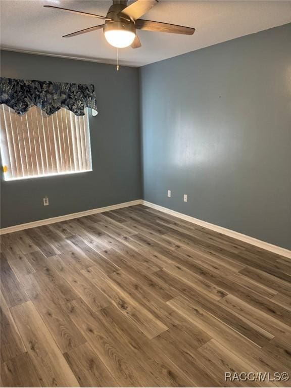 unfurnished room with wood finished floors, baseboards, and ceiling fan