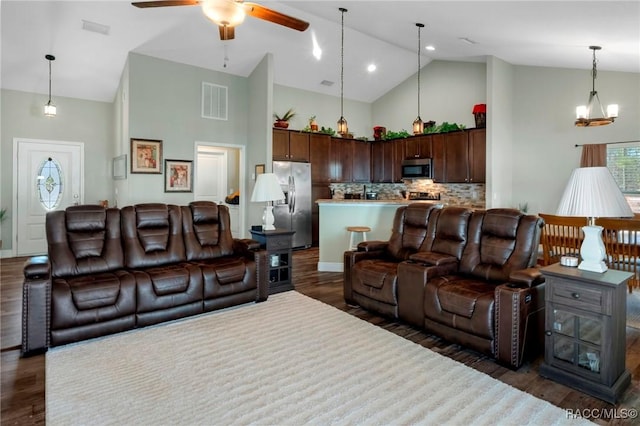 living area featuring dark wood-type flooring, visible vents, ceiling fan, and high vaulted ceiling