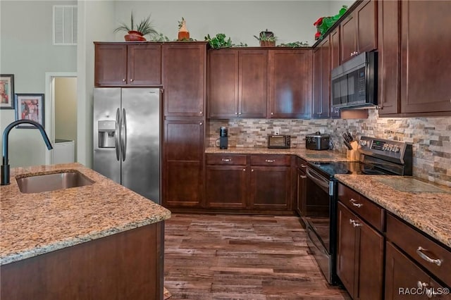 kitchen featuring light stone counters, tasteful backsplash, visible vents, appliances with stainless steel finishes, and a sink