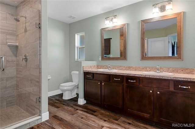 bathroom featuring double vanity, toilet, a sink, and wood finished floors