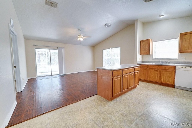 kitchen with lofted ceiling, sink, a center island, white dishwasher, and ceiling fan