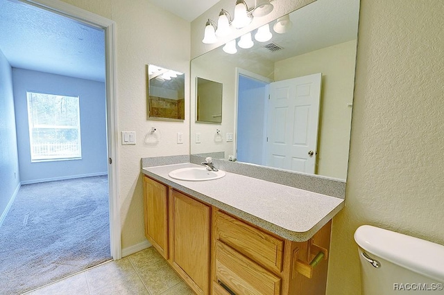 bathroom featuring vanity, tile patterned flooring, a textured ceiling, and toilet