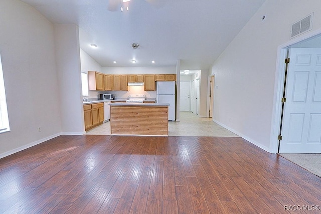 kitchen with sink, white appliances, light wood-type flooring, and a kitchen island