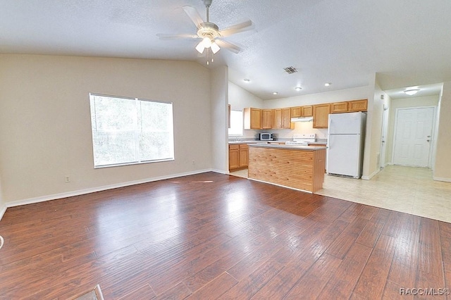 kitchen featuring lofted ceiling, white appliances, light hardwood / wood-style flooring, ceiling fan, and a textured ceiling