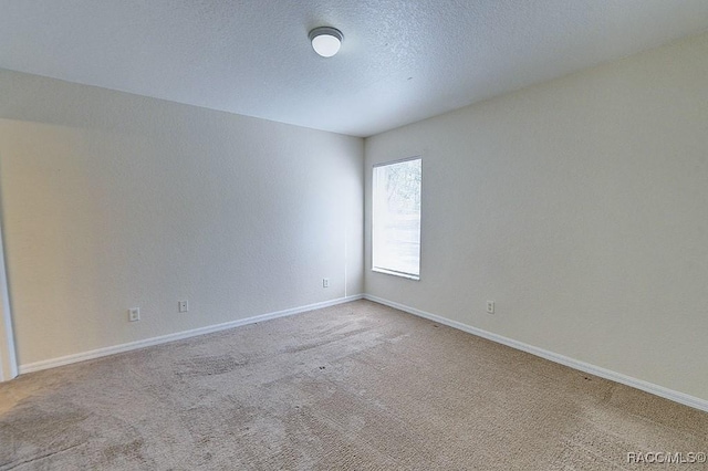 empty room with light carpet and a textured ceiling