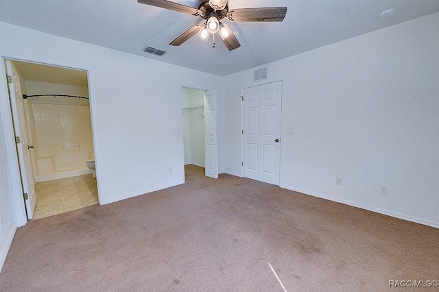 unfurnished bedroom with ensuite bathroom, light colored carpet, ceiling fan, and a closet