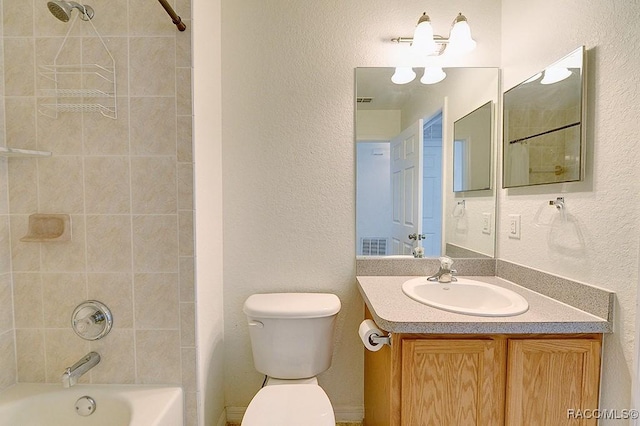 full bathroom featuring tiled shower / bath, vanity, and toilet