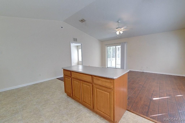 kitchen featuring vaulted ceiling, a center island, ceiling fan, and light wood-type flooring