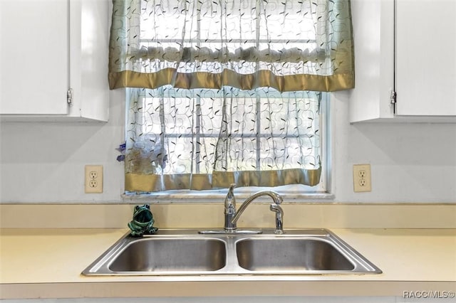 kitchen featuring light countertops, a sink, and white cabinetry