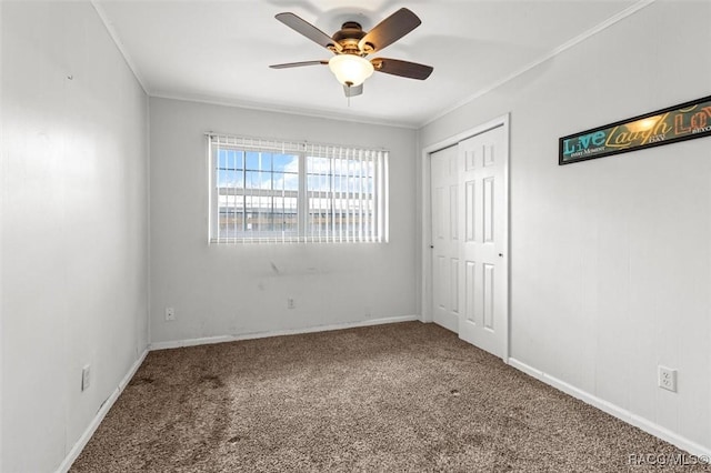 unfurnished bedroom featuring carpet floors, a closet, baseboards, and crown molding