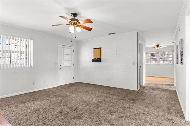 unfurnished room featuring visible vents, brick wall, ceiling fan, crown molding, and carpet floors