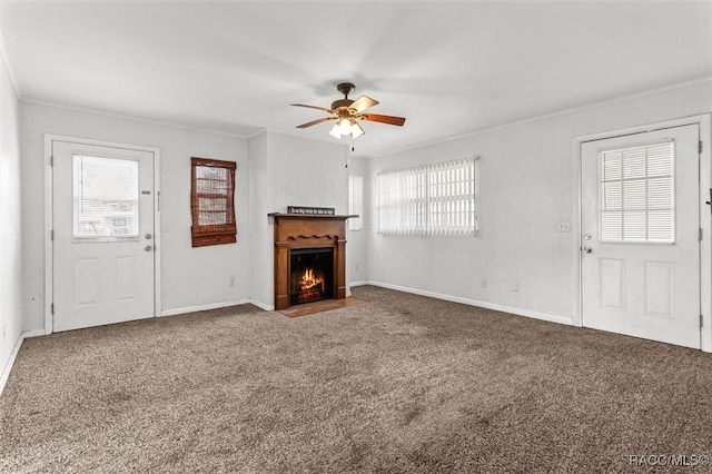 unfurnished living room with baseboards, a ceiling fan, a fireplace with flush hearth, ornamental molding, and carpet flooring