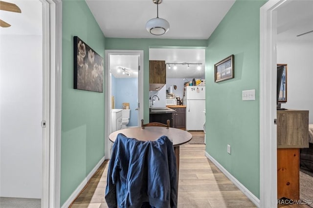 dining room featuring rail lighting, light wood-style flooring, baseboards, and a ceiling fan