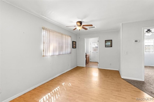 spare room with visible vents, baseboards, ceiling fan, crown molding, and light wood-type flooring