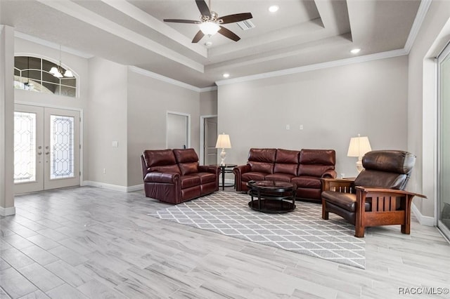 living room featuring french doors, ornamental molding, a high ceiling, and a tray ceiling