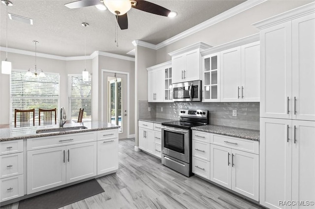 kitchen featuring pendant lighting, sink, appliances with stainless steel finishes, light stone counters, and white cabinets