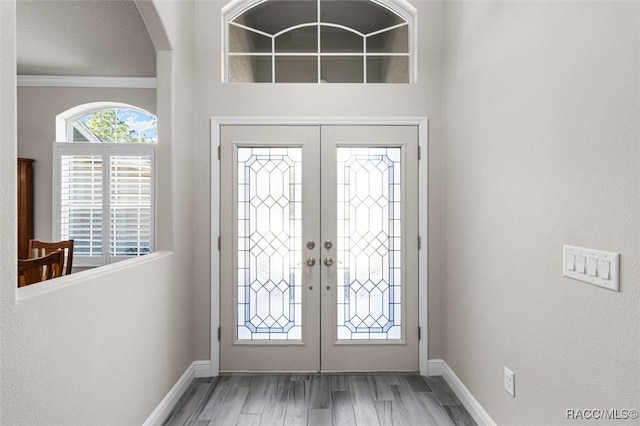 foyer featuring hardwood / wood-style flooring, ornamental molding, and french doors