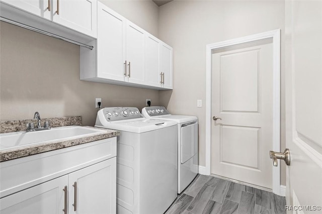 laundry area featuring cabinets, washing machine and dryer, sink, and light hardwood / wood-style flooring