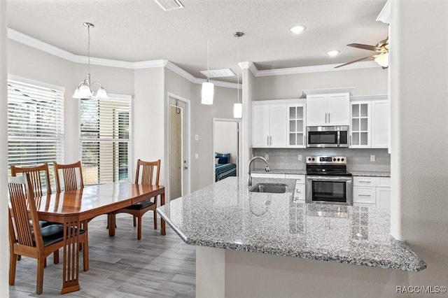 kitchen with white cabinetry, sink, decorative light fixtures, and appliances with stainless steel finishes