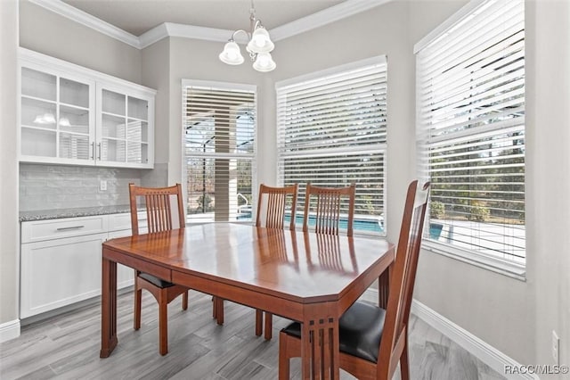 dining area featuring an inviting chandelier, ornamental molding, and light hardwood / wood-style flooring