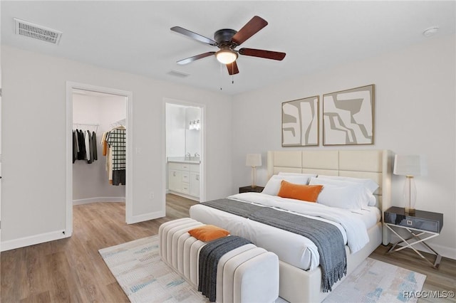 6658 N Bedstrow Blvd, Dunnellon, FL 34434 - bedroom with wood finished floors, a spacious closet, a ceiling fan, and connected bathroom