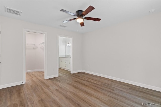 6658 N Bedstrow Blvd, Dunnellon, FL 34434 - unfurnished bedroom with a walk in closet, light wood-style flooring, ceiling fan, and connected bathroom