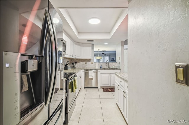 kitchen with appliances with stainless steel finishes, backsplash, a tray ceiling, sink, and white cabinets